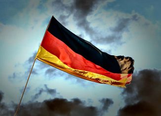 Na zdjęciu znajduje się flaga Niemiec na tle zachmurzonego nieba.
